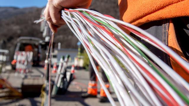 Un travailleur de Swisscom installe de la fibre optique près de Bellinzone (TI), en février 2015. [Keystone - Carlo Reguzzi]