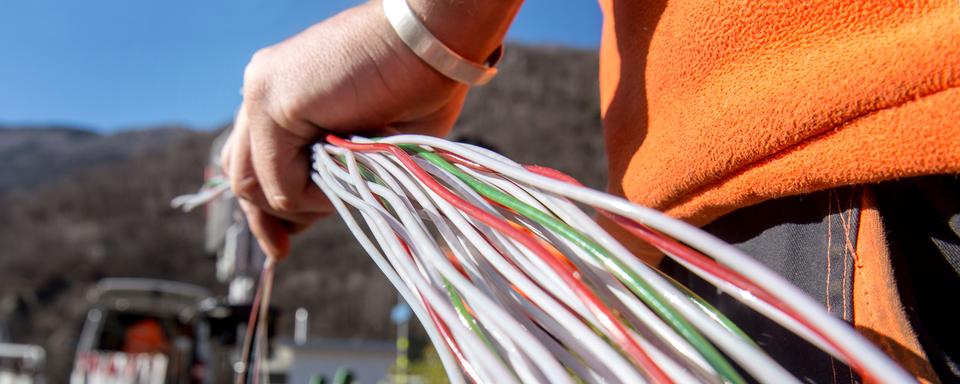 Un travailleur de Swisscom installe de la fibre optique près de Bellinzone (TI), en février 2015. [Keystone - Carlo Reguzzi]