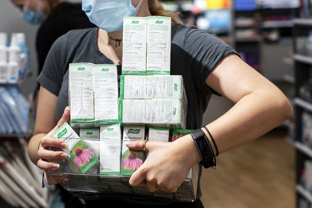 Une employée de pharmacie porte des paquets d'Echinarforce, un remède à base d'échinacée utilisé pour lutter contre les refroidissements en hiver. [Keystone - Alexandra Wey]