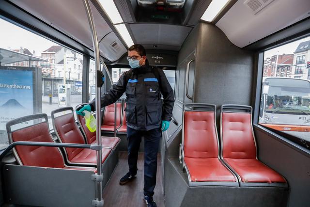 Un employé de la STIB (les transports publics bruxellois) désinfecte un bus à son arrivée au terminus. Le port d'un masque est obligatoire à partir de lundi dans les transports publics pour toutes les personnes âgées de plus de 12 ans. Bruxelles, le 4 mai 2020. [Keystone/epa - Stéphanie Lecocq]