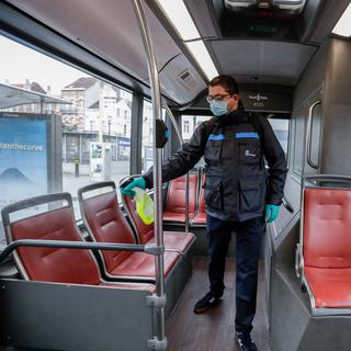 Un employé de la STIB (les transports publics bruxellois) désinfecte un bus à son arrivée au terminus. Le port d'un masque est obligatoire à partir de lundi dans les transports publics pour toutes les personnes âgées de plus de 12 ans. Bruxelles, le 4 mai 2020. [Keystone/epa - Stéphanie Lecocq]