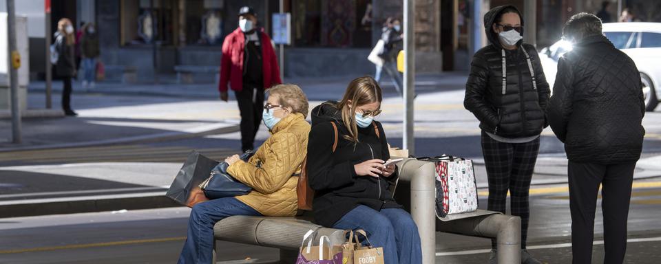 Des personnes masquées à un arrêt de transport public, le 27 octobre 2020 à Lugano. [Keystone - Davide Agosta]