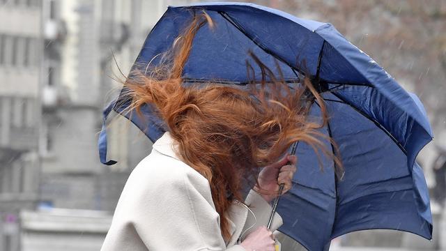 Une femme et son parapluie se battent contre le vent, le 15 mars 2019 à Zurich. [Keystone - Walter Bieri]