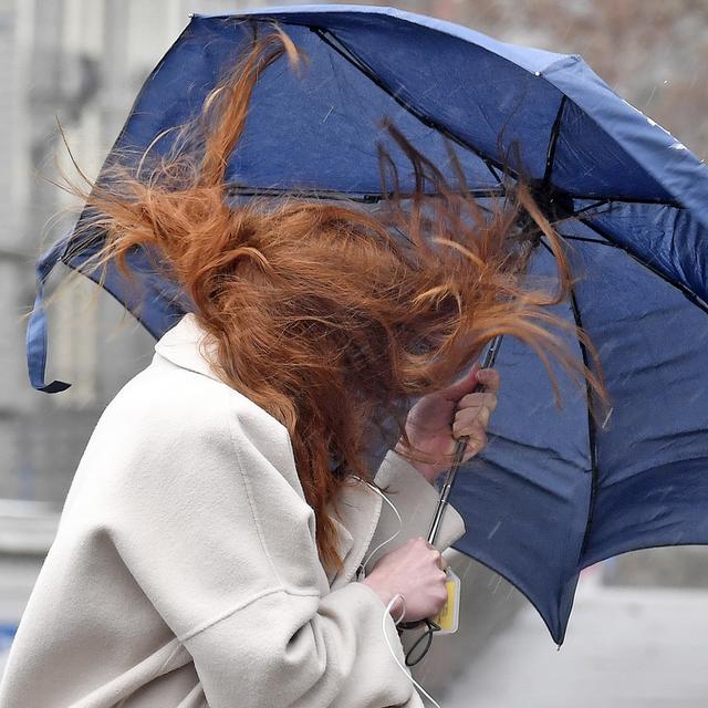 Une femme et son parapluie se battent contre le vent, le 15 mars 2019 à Zurich. [Keystone - Walter Bieri]