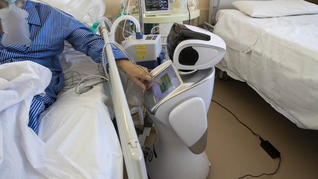 Un robot auprès d'un patient atteint du coronavirus dans un hôpital italien. [Keystone - AP Photo/Luca Bruno]