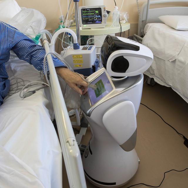 Un robot auprès d'un patient atteint du coronavirus dans un hôpital italien. [Keystone - AP Photo/Luca Bruno]