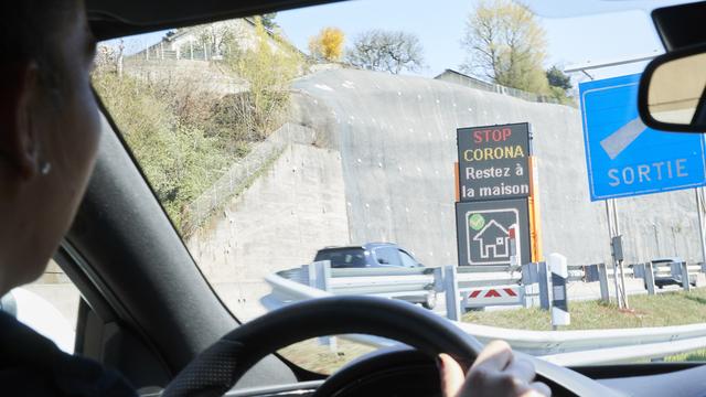 Un panneau vu depuis l'intérieur d'une voiture de police vaudoise incite la population à rester chez elle. [Keystone - Denis Balibouse]