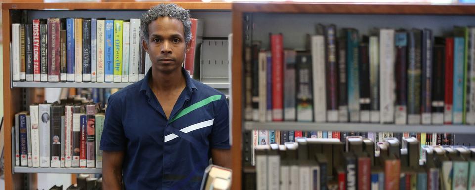 L'écrivain David Chariandy dans une bibliothèque de Toronto. [Toronto Star via Getty Images - Steve Russell]