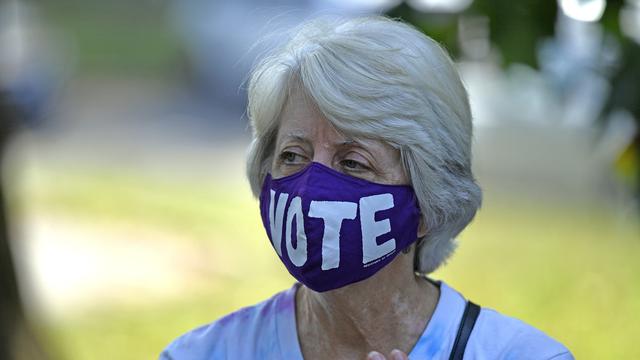 Une femme américaine portant un masque appelant à voter. [Keystone/AP Photo - Timothy D. Easley]