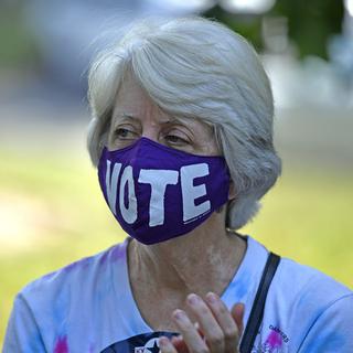 Une femme américaine portant un masque appelant à voter. [Keystone/AP Photo - Timothy D. Easley]