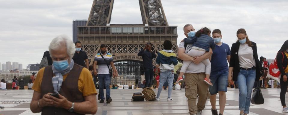 Des touristes masqués devant la tour Eiffel, le 27 août 2020. [AFP - Mehdi Taamallah]