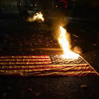 Un drapeau américain en flamme, dans l'Oregon le 3 novembre 2020. [Keystone/AP Photo - Marcio Jose Sanchez]