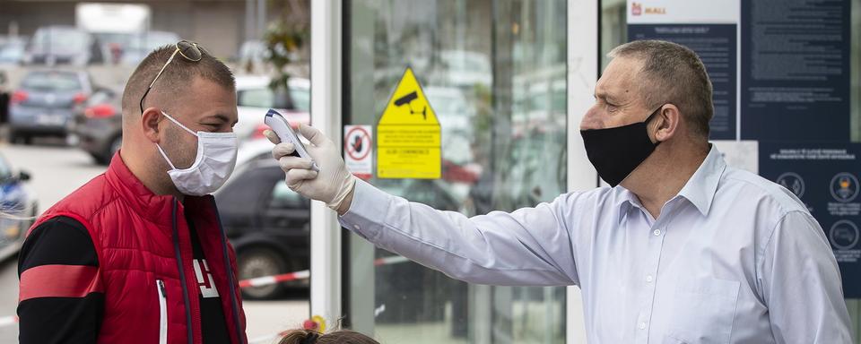 Contrôle de température à l'entrée d'un centre commercial à Pristina, au Kosovo. [Keystone - EPA/Valdrin Xhemaj]