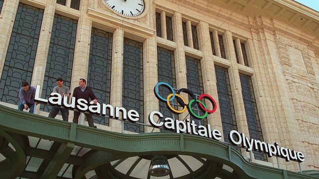 Des ouvriers installent le panneau lumineux "Lausanne capitale olympique" au-dessus de l'entree principale de la gare de Lausanne, en 1997. [Keystone - Fabrice Coffrini]