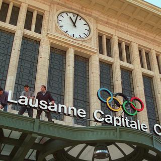 Des ouvriers installent le panneau lumineux "Lausanne capitale olympique" au-dessus de l'entree principale de la gare de Lausanne, en 1997. [Keystone - Fabrice Coffrini]