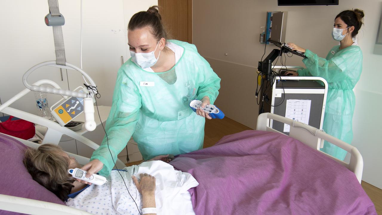 Deux infirmières au chevet d'une patiente à l'Hôpital Riviera-Chablais à Rennaz. [Keystone - Laurent Gilliéron]