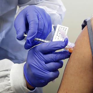 Un patient reçoit une injection dans le cadre de la première phase de l'étude de sécurité d'un vaccin potentiel pour COVID-19 à Seattle le 16 mars 2020. [Keystone - AP Photo/Ted S. Warren, File]
