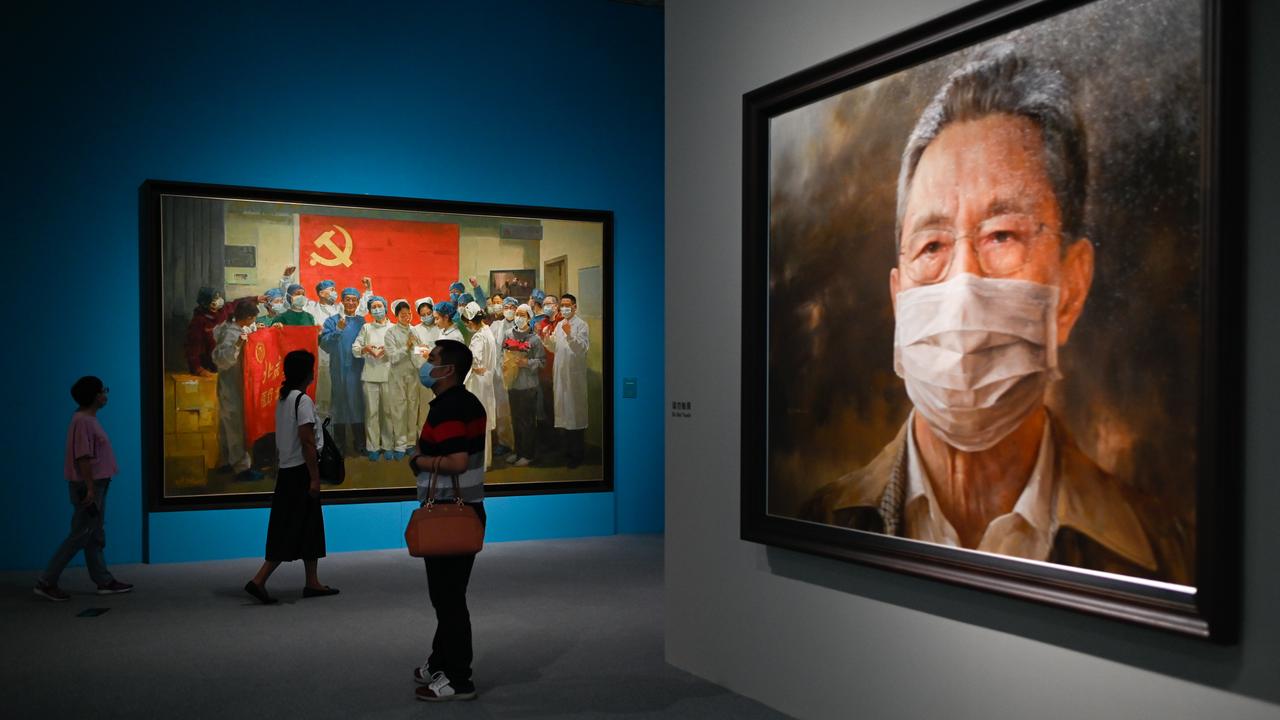 Des gens visitent une exposition sur le coronavirus à Pékin. On peut notamment voir ici, un tableau du célèbre pneumologue Zhanh Nanshan (à droite) réalisé par l'artiste Feng Zhaoxie. [afp - STR]