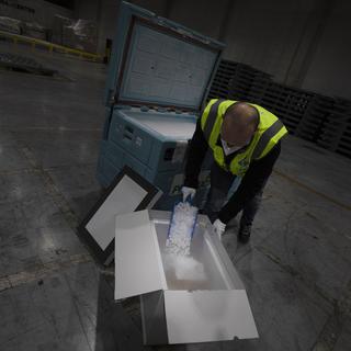 Des travailleurs spécialisés dans la logistique s'entraînent à manipuler des vaccins dans la glace sèche dans un entrepôt en Belgique. [Keystone - Virginia Mayo]