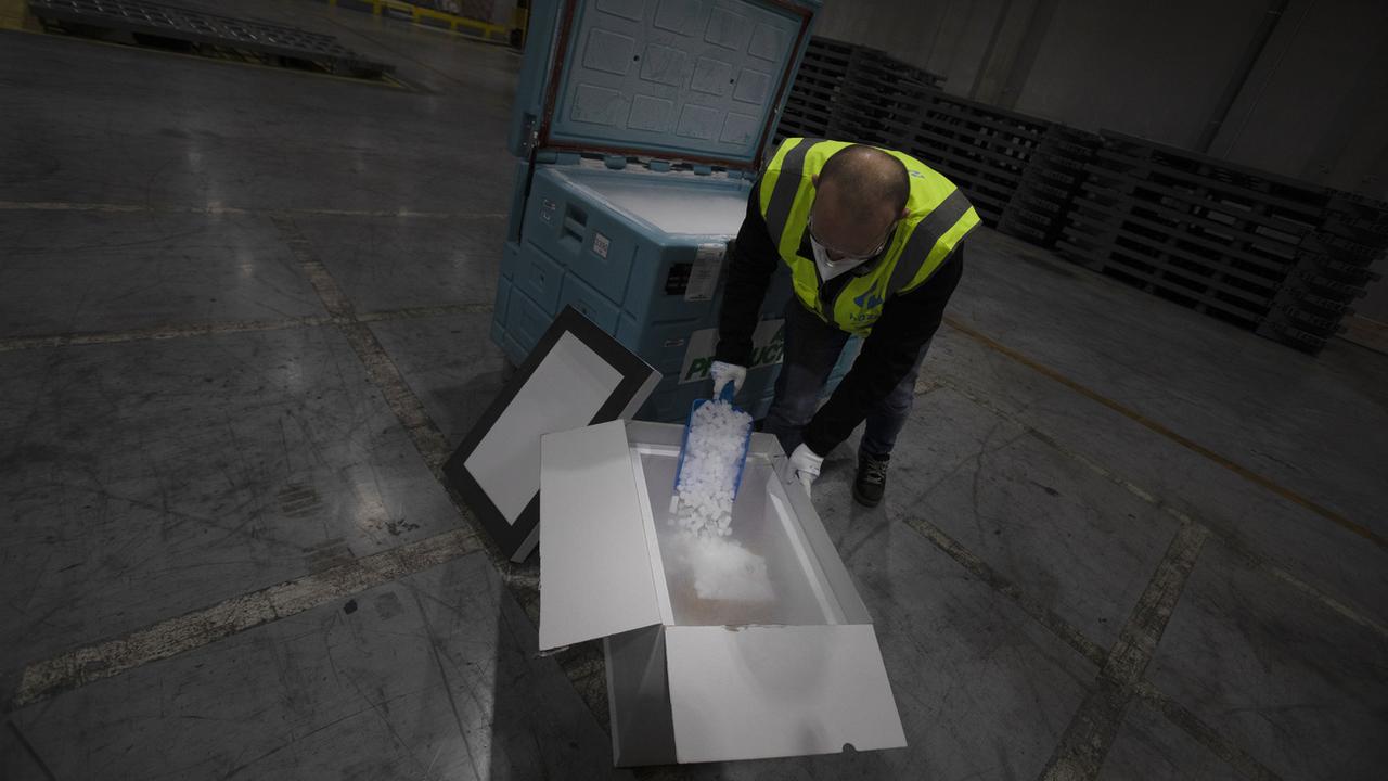 Des travailleurs spécialisés dans la logistique s'entraînent à manipuler des vaccins dans la glace sèche dans un entrepôt en Belgique. [Keystone - Virginia Mayo]