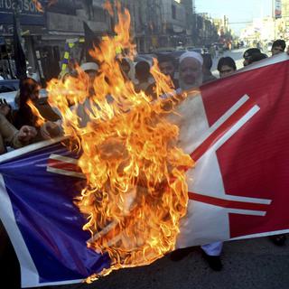 Des manifestants pakistanais brûlent un drapeau français. [Keystone/AP Photo - Muhammad Sajjad]
