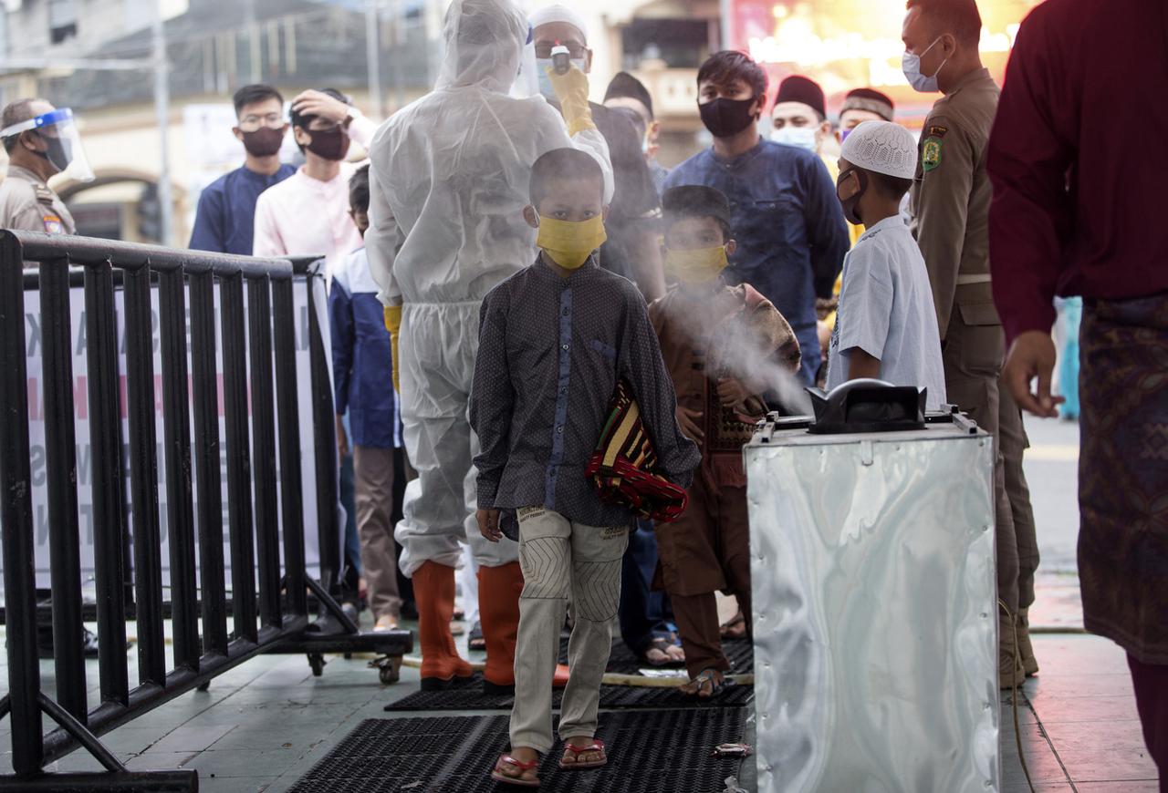 En Indonésie, les participants à la prière de l'Aïd passent devant un spray de désinfectant après que leur température aie été contrôlée. [Keystone - Binsar Bakkara]