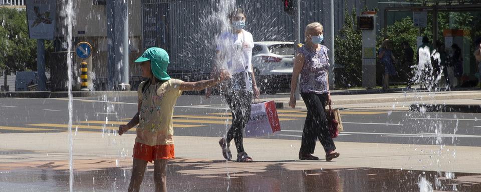 Une fille joue avec des jets d'eau. [Keystone - Salvatore Di Nolfi]