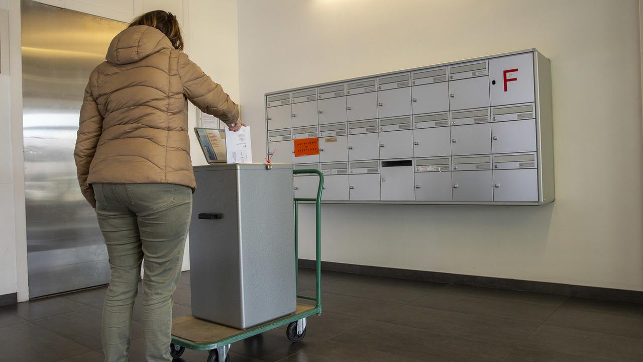 Une personne met son enveloppe dans la boîte aux lettres du Service des votations et élections de la Chancellerie, Genève, mars 2020. [Keystone - Salvatore Di Nolfi]