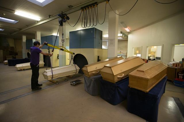 Un technicien prépare l'entrée d'un cercueil dans l'un des fours de crémation du centre funéraire du cimetière Saint Georges. Le service des pompes funèbres de la Ville de Genève ne sait plus où donner de la tête a cause de la crise sanitaire. [Keystone - Salvatore Di Nolfi]