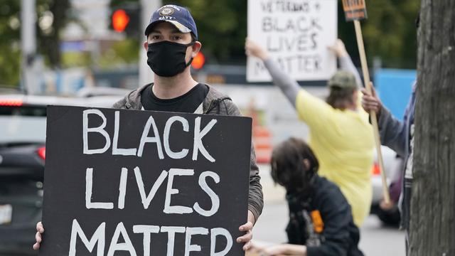 Un manifestant avec une pancarte "Black lives matter". [AP Photo/Kestone - Tony Dejak]