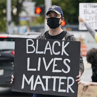 Un manifestant avec une pancarte "Black lives matter". [AP Photo/Kestone - Tony Dejak]