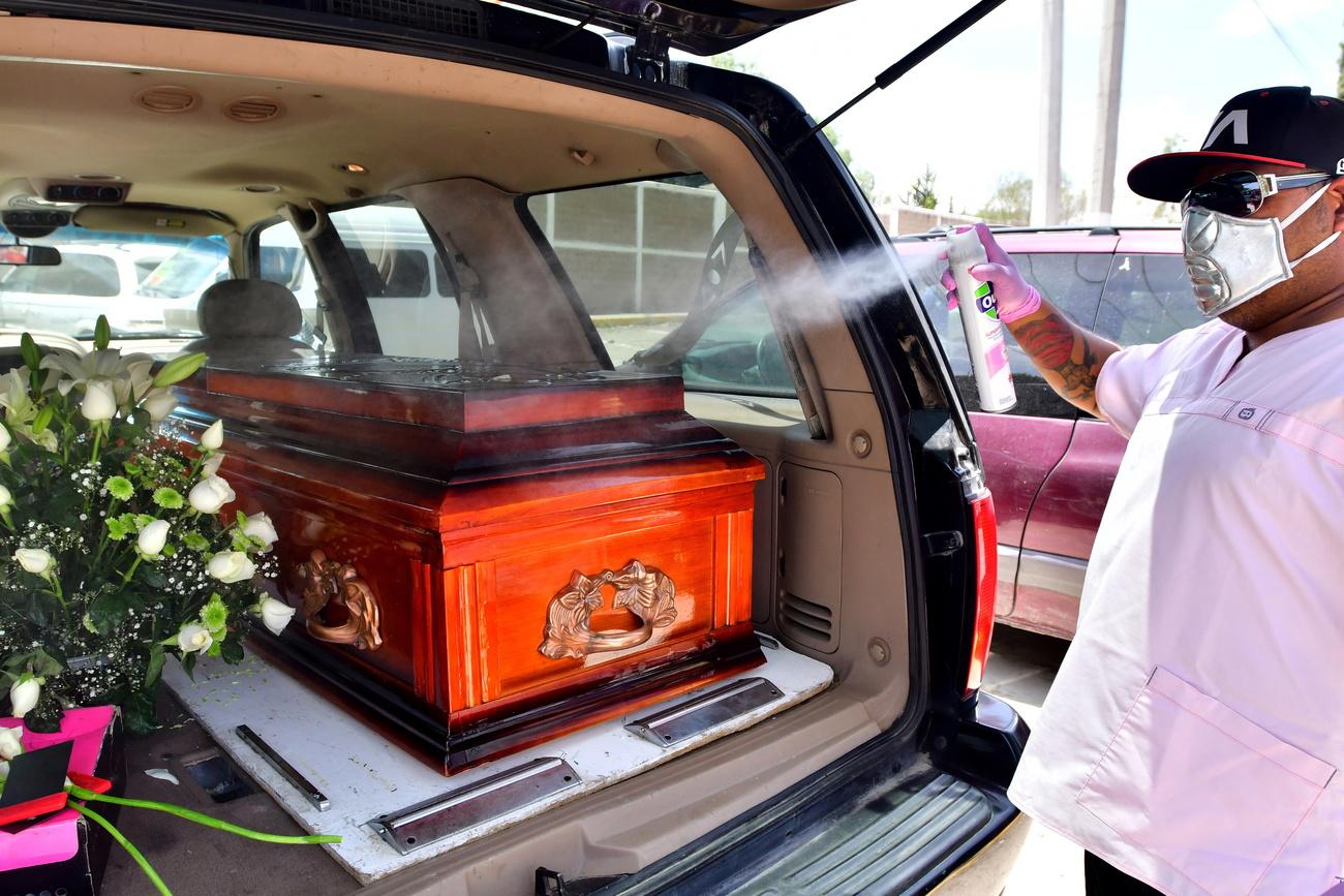 Un travailleur funéraire désinfecte un cercueil à son arrivée au cimetière de San Isidro. Beaucoup de gens pensent que la maladie n'existe pas, bien que le nombre de morts dues au Covid-19 a doublé durant la seconde moitié du mois de juin. Mexique, le 2 juillet 2020. [Keystone/EPA - Jorge Nunez]