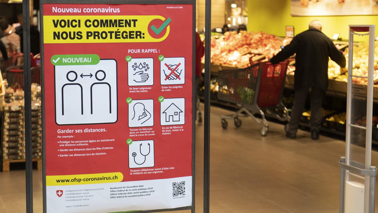 Une affiche de prévention à l'entrée d'un supermarché. [Keystone - Laurent Gillieron]