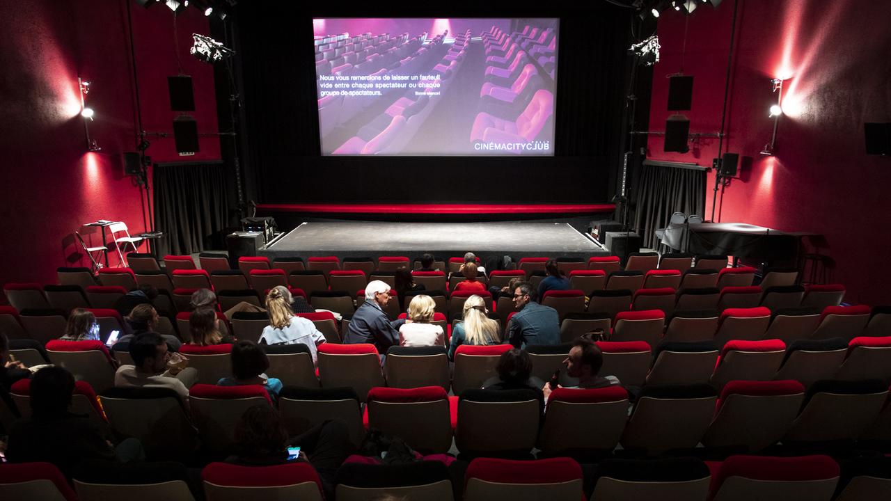 Des personnes s'installent avant de visionner le film "L'île aux oiseaux" dans la salle de projection du Cinema CityClub le jour de sa réouverture lors de la pandémie de Coronavirus (Covid-19) le 6 juin 2020 à Pully près de Lausanne. [Keystone - Laurent Gillieron]