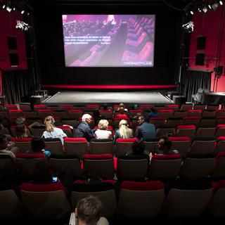 Des personnes s'installent avant de visionner le film "L'île aux oiseaux" dans la salle de projection du Cinema CityClub le jour de sa réouverture lors de la pandémie de Coronavirus (Covid-19) le 6 juin 2020 à Pully près de Lausanne. [Keystone - Laurent Gillieron]