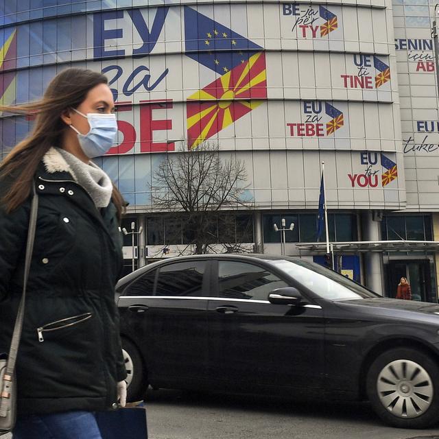 Une femme passe devant le bureau de l'UE décoré par des drapeaux de la Macédoine du Nord et de l'Union européenne à Skopje. [Keystone - EPA/GEORGI LICOVSKI]