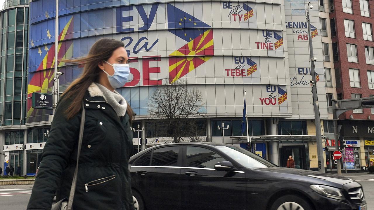 Une femme passe devant le bureau de l'UE décoré par des drapeaux de la Macédoine du Nord et de l'Union européenne à Skopje. [Keystone - EPA/GEORGI LICOVSKI]