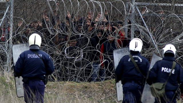 Migrants entassés contre les barbelés face à la police grecque à Kastanies, 04.03.2020. [AP/Keystone - Giannis Papanikos]