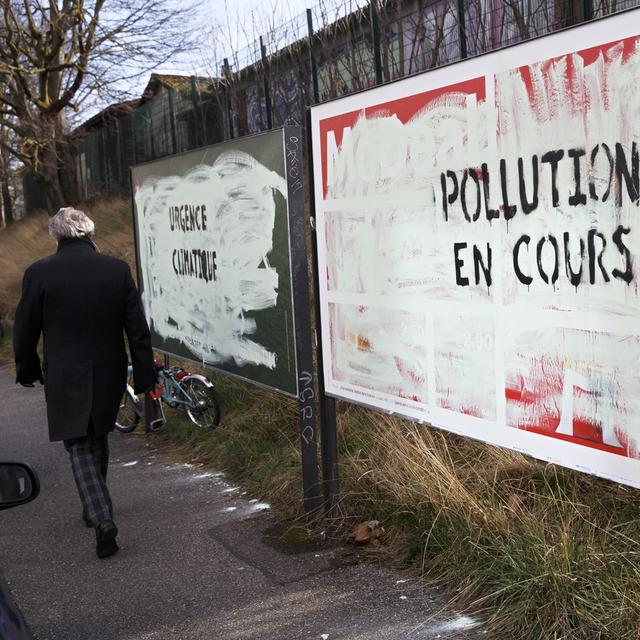 Affiches publicitaires recouvertes de peinture avec le message "Pollution en cours" à Genève le 12 mars 2019. [Keystone - Salvatore Di Nolfi]