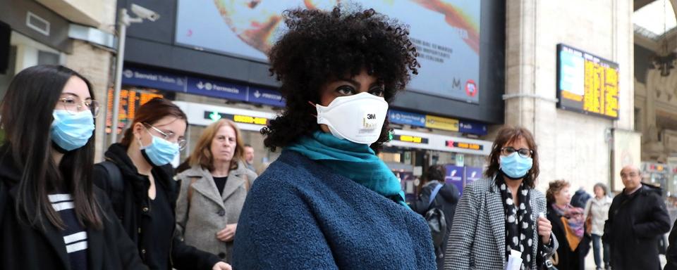 Des voyageurs portant des masques de protection à la gare centrale de Milan en Italie. [KEYSTONE - MATTEO BAZZI / EPA]