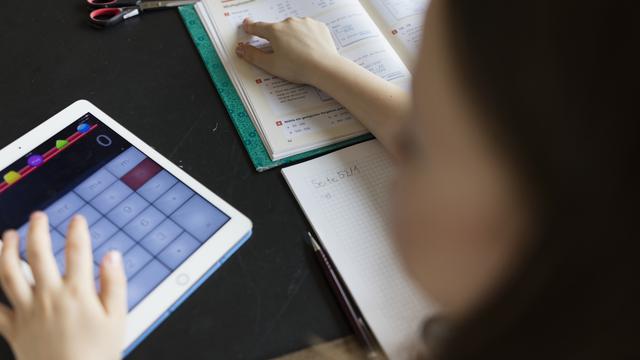 Une écolière utilise une tablette pour un exercice de mathématiques. [Keystone - Gaetan Bally]