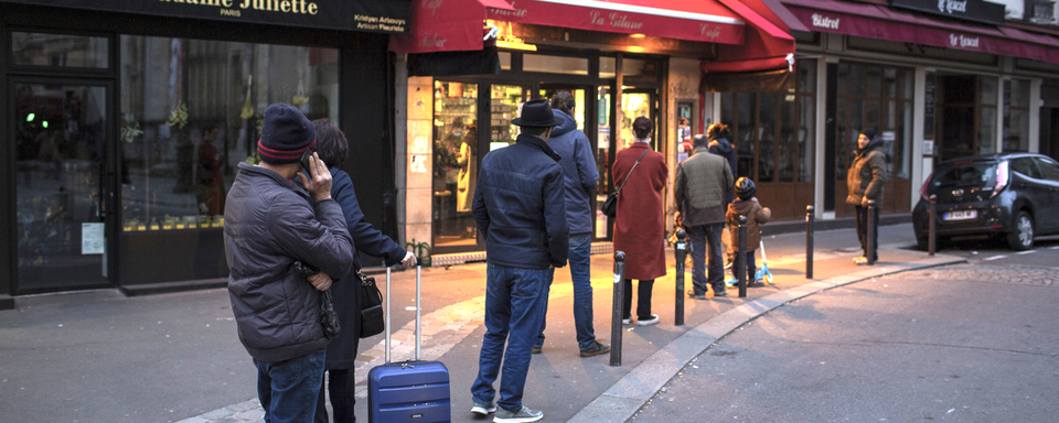 Des personnes font la queue à l'entrée d'un commerce parisien en respectant les distances. [AP/Keystone - Rafael Yaghobzadeh]