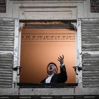 Le chanteur d'opéra français Stéphane Senechal chante "O Sole Mio" à sa fenêtre le 26 mars 2020 à Paris. [AFP - PHILIPPE LOPEZ]