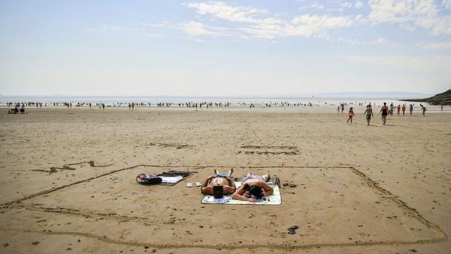 Deux personnes prennent le soleil dans un carré de quatre mètres carrés tracé dans le sable. Plage de Barry Islande, Pays de Galles, le 31 juillet 2020. [Keystone/PA via AP - Ben Birchall]