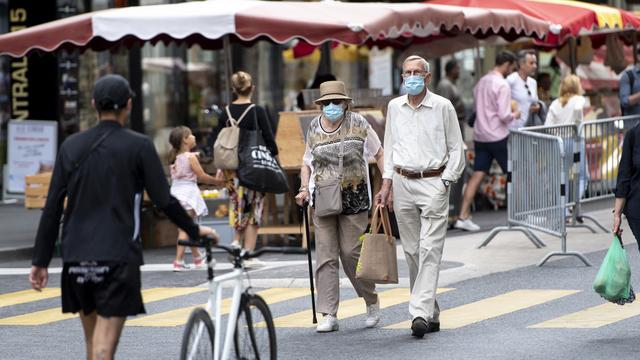 Des personnes, masquées ou non, flânent entre les stands du marché de Lausanne, le 23 mai 2020. [Keystone - Laurent Gillieron]