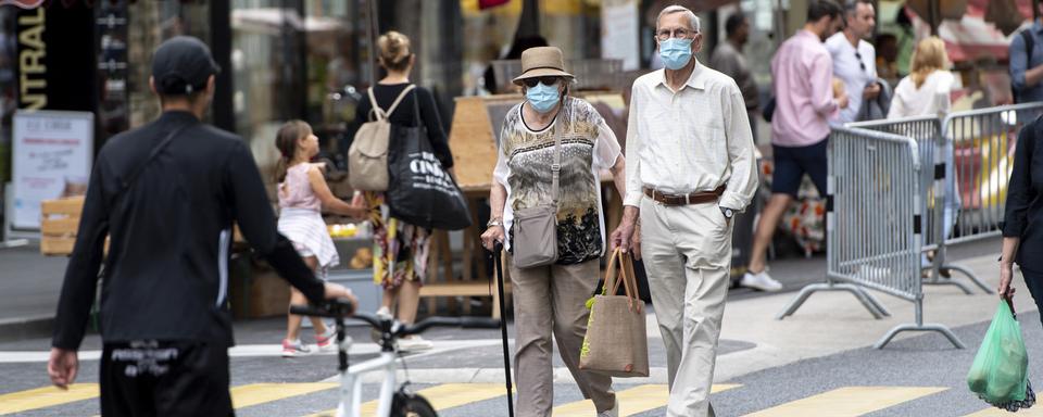 Des personnes, masquées ou non, flânent entre les stands du marché de Lausanne, le 23 mai 2020. [Keystone - Laurent Gillieron]