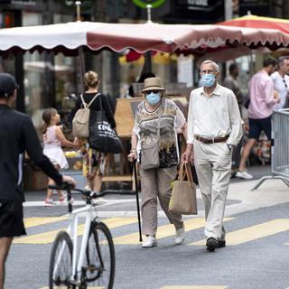 Des personnes, masquées ou non, flânent entre les stands du marché de Lausanne, le 23 mai 2020. [Keystone - Laurent Gillieron]