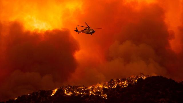 Un hélicoptère se prépare à déverser de l'eau sur le feu du Lake Hugues, au nord de Santa Clarita. Californie, le 12 août 2020. [Keystone/AP Photo - Ringo H.W. Chiu]