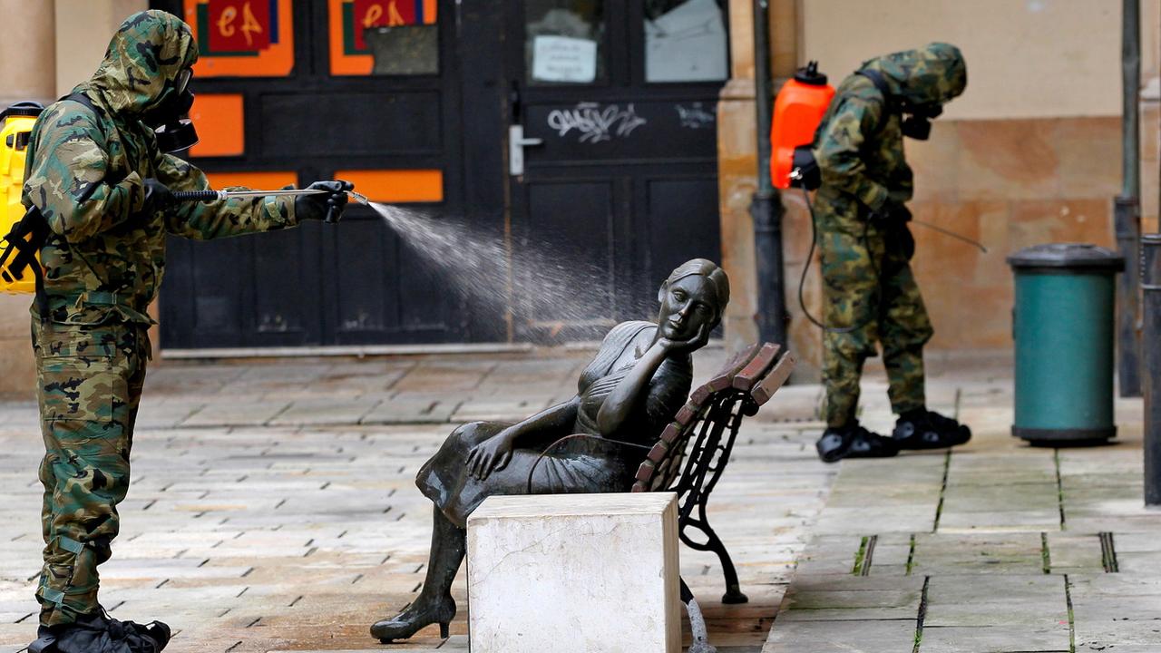 Un soldat désinfecte la statue "La Bella Lola" à Oviedo, dans le nord de l'Espagne, le 12 avril 2020. [Keystone/epa - Alberto Morante]