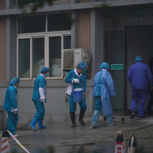Le personnel du Wuhan Medical Treatment Center nettoie l'entrée du bâtiment pour éviter les cas de contamination par le nouveau coronavirus chinois. [Keystone/Dake Kang - Dake Kang]